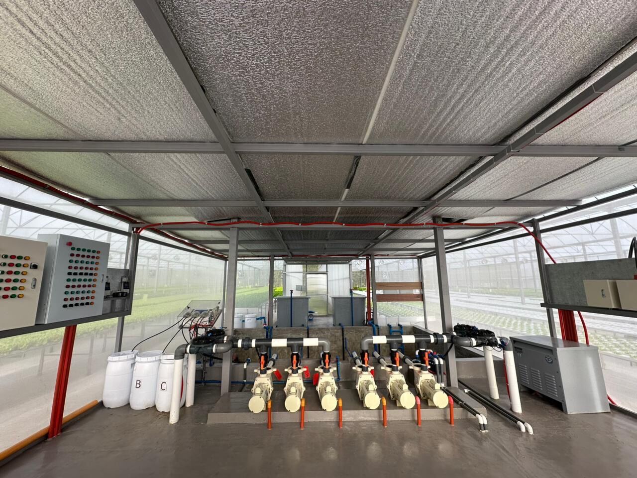 Wide view of the SAREEWÂ fertigation room, with the nutrient dosing pump bank, control panel, and mixing tanks